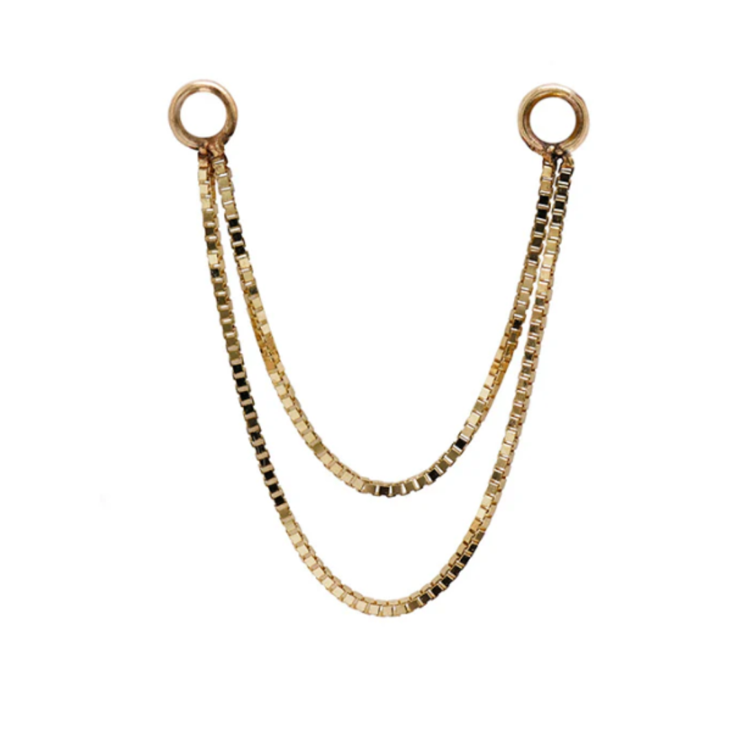 Close-up of a Quetzalli Double Box Chain made from solid gold, featuring two sleek rows of box-cut links joined by circular ends, designed for connecting multiple piercings in a luxury style.