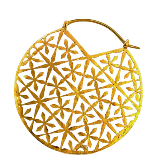 Quetzalli Epiphany Hollow hoop earring crafted from yellow brass with an anodised titanium clasp, featuring a large circular design with cut-out geometric floral patterns, photographed against a white background.