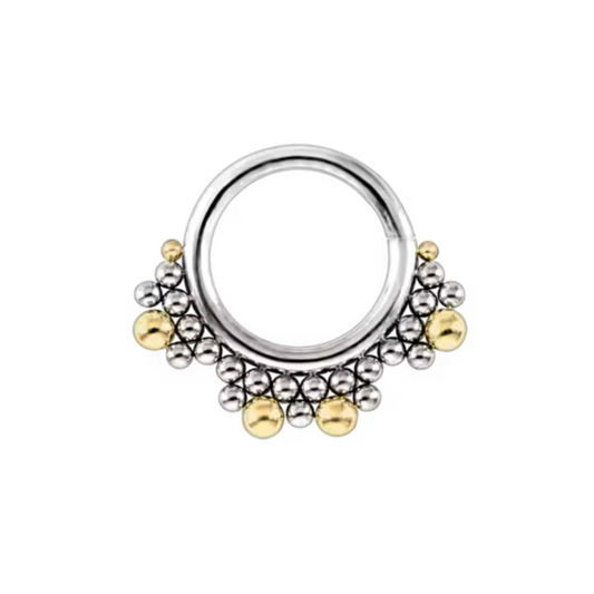 High-end piercing jewellery featuring a polished titanium clicker ring with layered beaded detailing and accent gold spheres, designed for septum or daith piercings with a luxury finish.